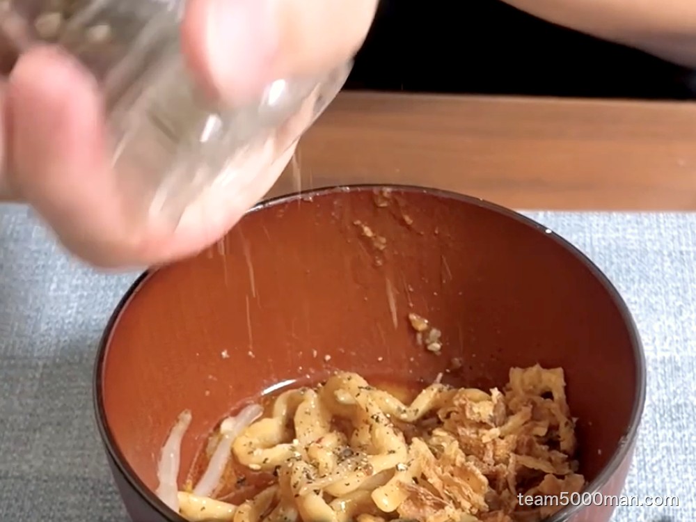 小分け皿に取った麺にフライドオニオンとブラックペッパーをかけて味変