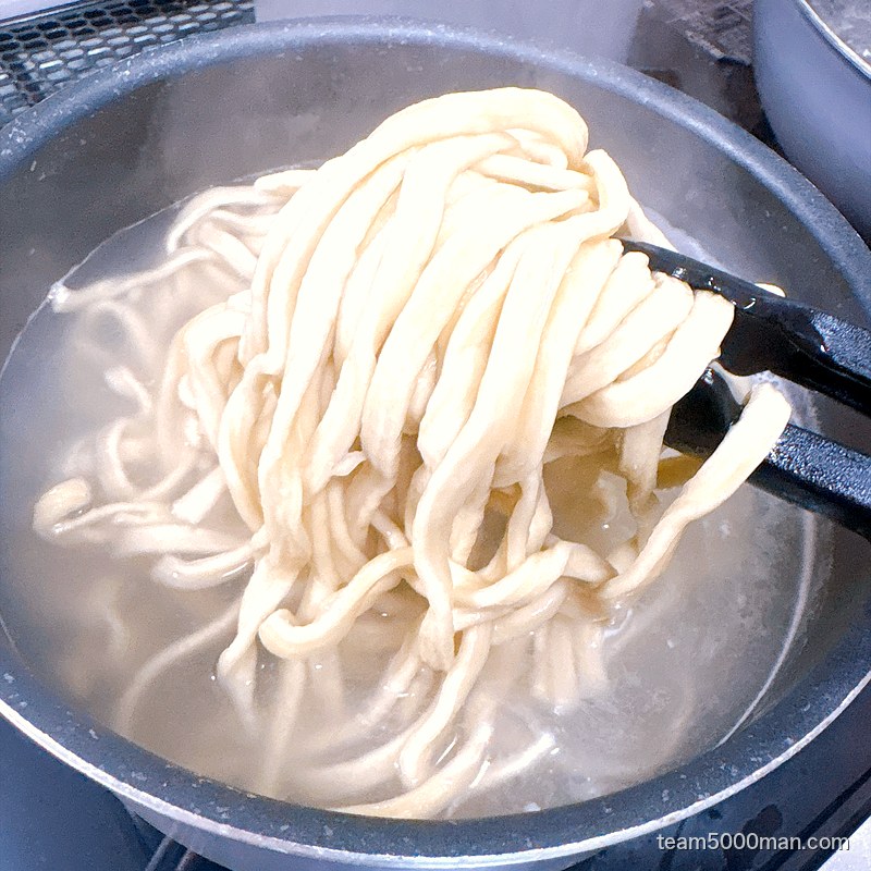 鍋の中で茹でているえびラーメンの極太麺