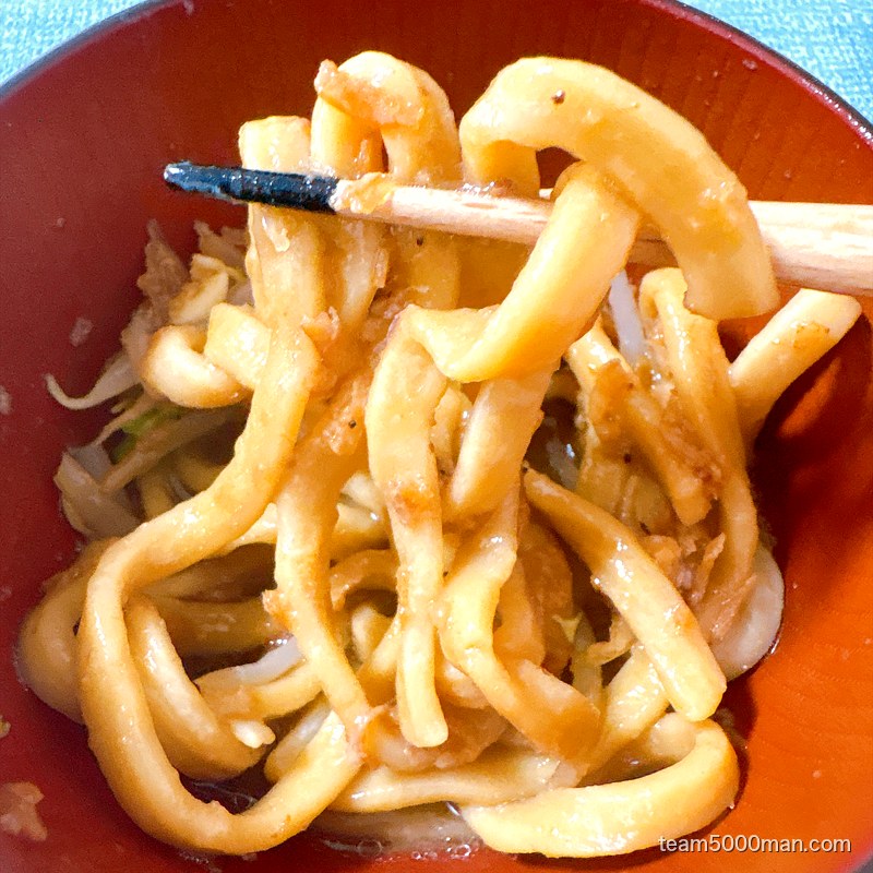 卵を絡めたえびラーメンの麺を持ち上げたところ