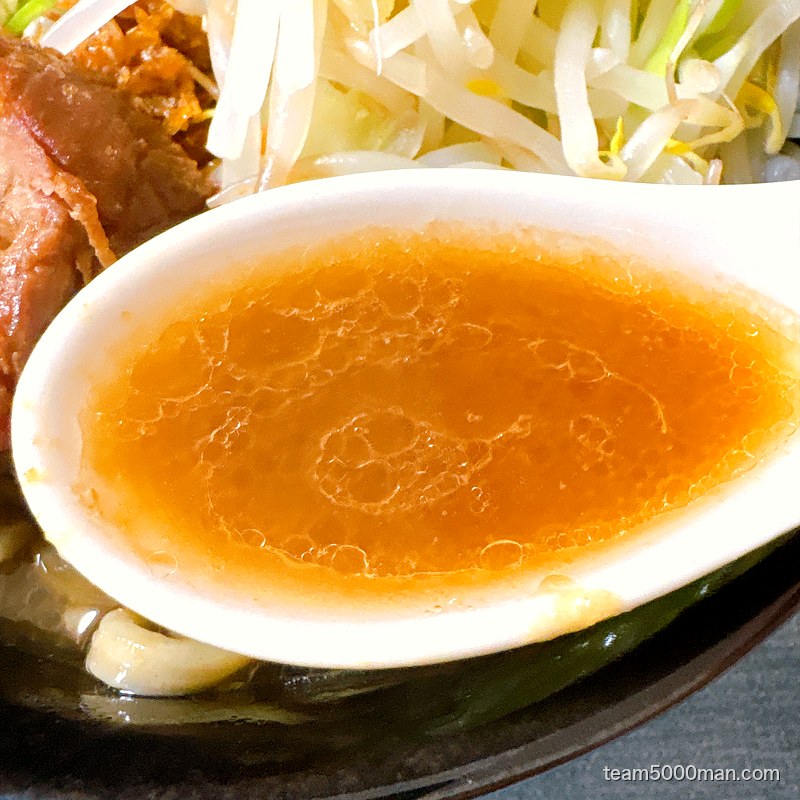 えびラーメンのスープをレンゲですくったところ。えび油で琥珀色に