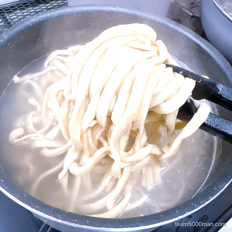 鍋の中で茹でているえびラーメンの極太麺