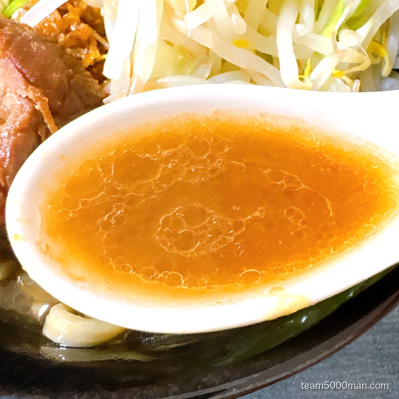 えびラーメンのスープをレンゲですくったところ。えび油で琥珀色に