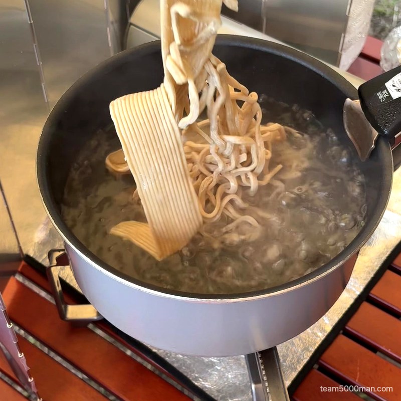 キャンプで宅麺 カセットコンロの鍋に麺でるの麺を入れる