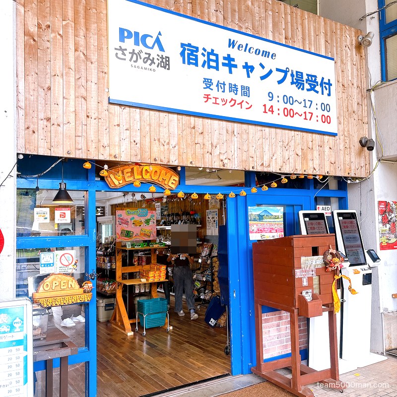PICAさがみ湖 宿泊キャンプ場受付の入口 受付時間とチェックイン時間の看板（人物はモザイク）